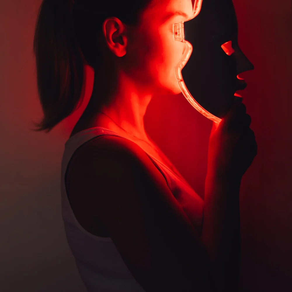Side view of a woman wearing the re-nū 8 Color LED Facial Mask with red light activated.