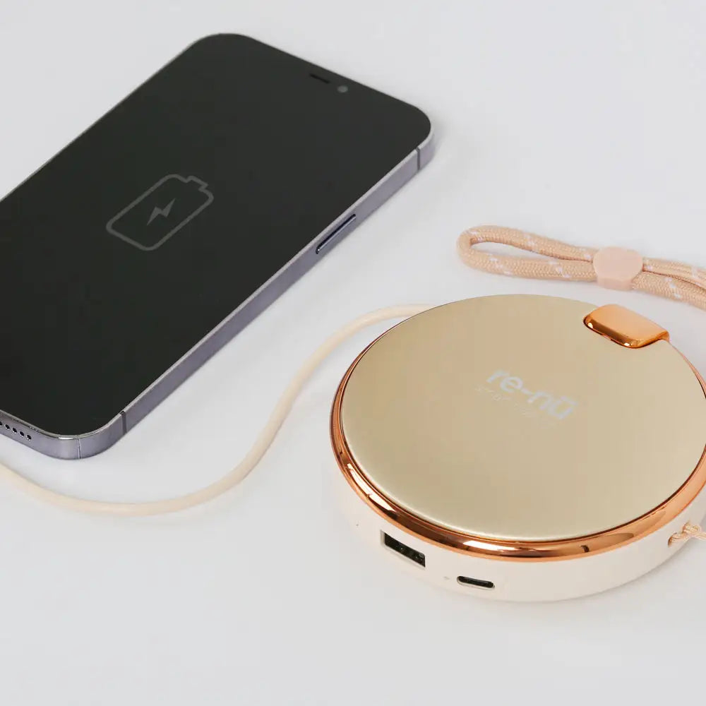 Closeup of the re-nū Hand Warmer connected to a smartphone via USB output cable, functioning as a portable power bank.