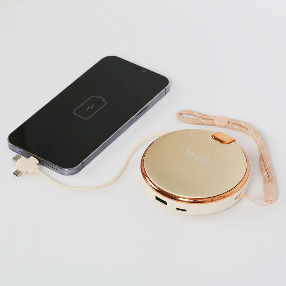 Beige color re-nū Hand Warmer connected to a smartphone via USB output cable, functioning as a portable power bank.