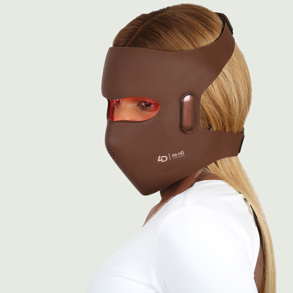 Woman wearing the world's first re-nū 4D Laser Light Therapy Mask with glowing red laser light illuminating her face.