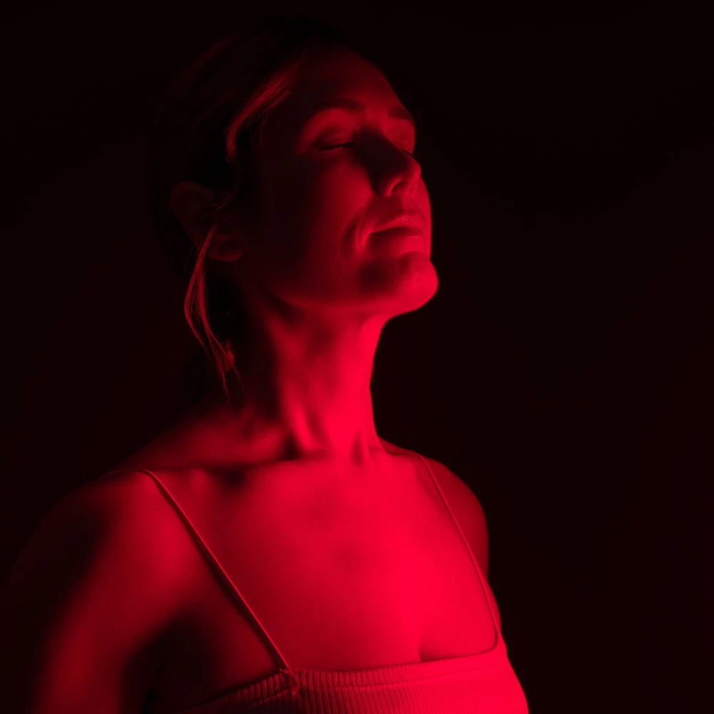 Woman using Clinical Grade Red LED & COB Light Therapy Panel with red light illuminating her face and neck, highlighting skin glow and rejuvenation.