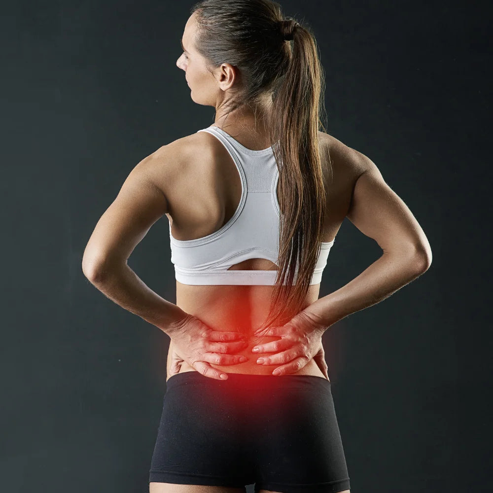 Woman touching her lower back to indicate discomfort or pain, highlighting the target area for red light therapy treatment.