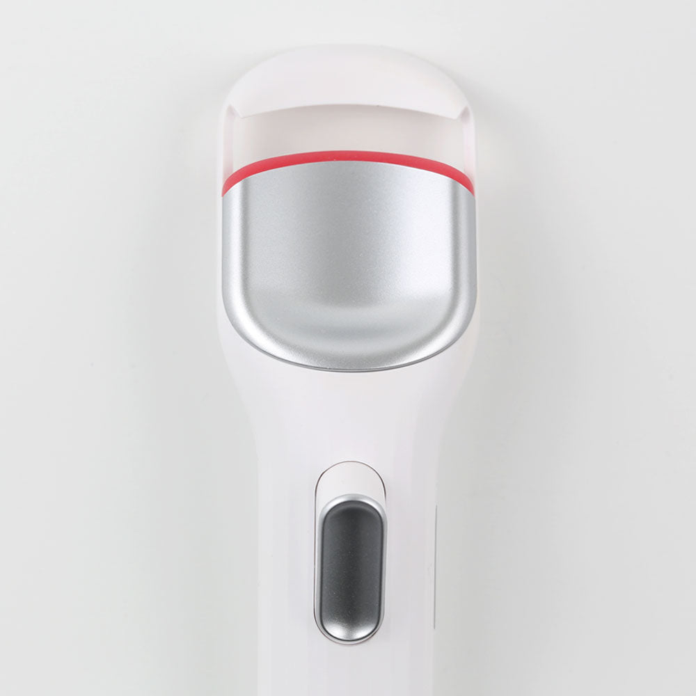 Close-up view of an electric heated eyelash curler with silicone pad and power button for easy curling.