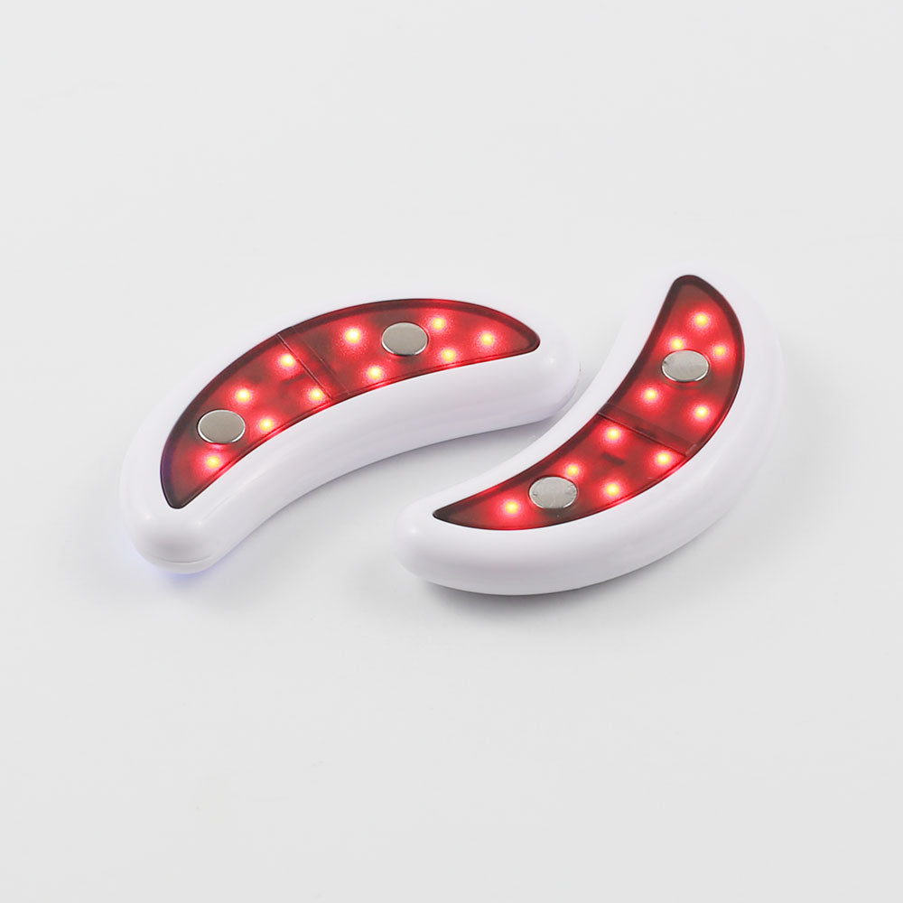 Close-up of the GlowUp LED/EMS Under Eye Anti-Aging Pads shows the glowing red LED light and ergonomic design, which fits seamlessly under your eyes to deliver salon-like results at home or on the go.