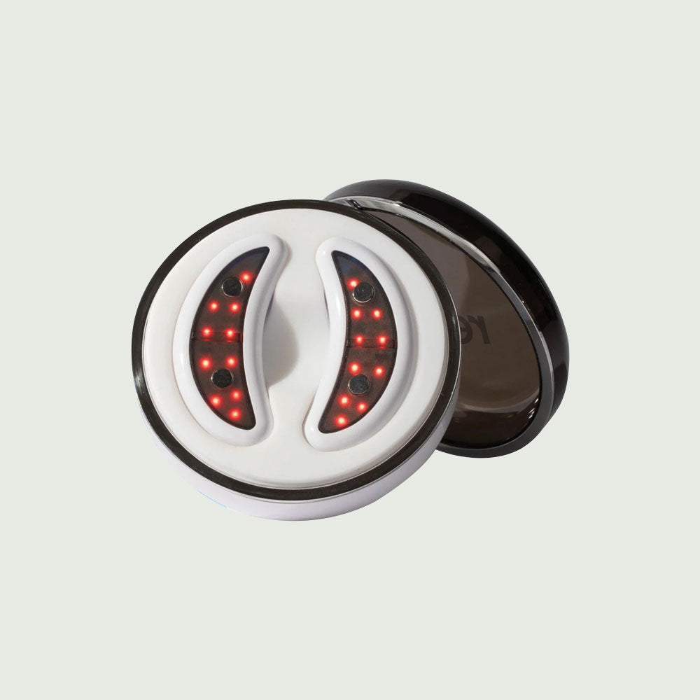 Front view of GlowUp LED/EMS Under Eye Anti-Aging Pads placed neatly in their sleek, round USB-C charging case.