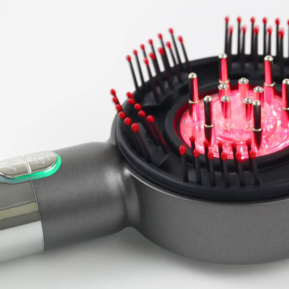 Closeup side view of the LED Therapy Massage Comb showing red light LEDs activated and mode button illuminated.