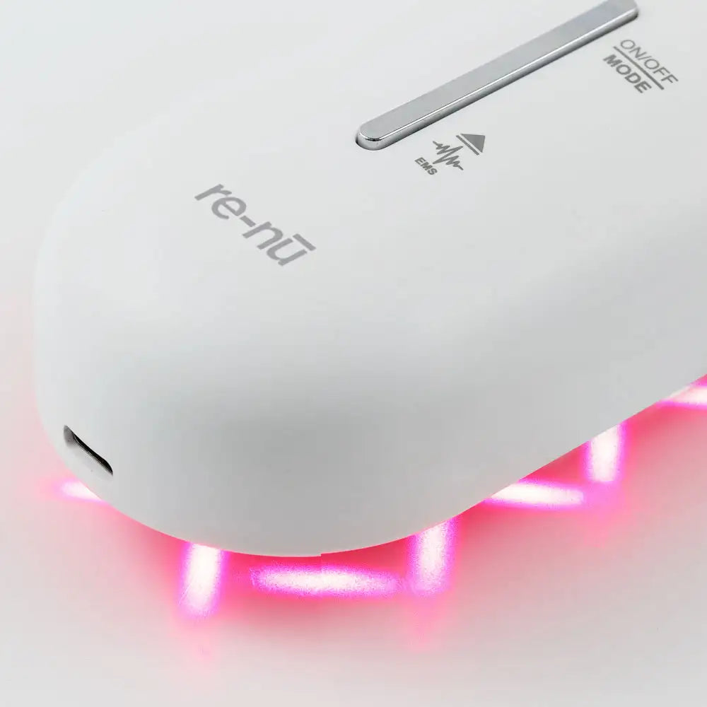 Closeup view of the Plasma Laser Therapy Hair Growth Comb by re-nū Smart Beauty, showing red laser reflection, easy to use EMS mode controls, and usb-c charging port.