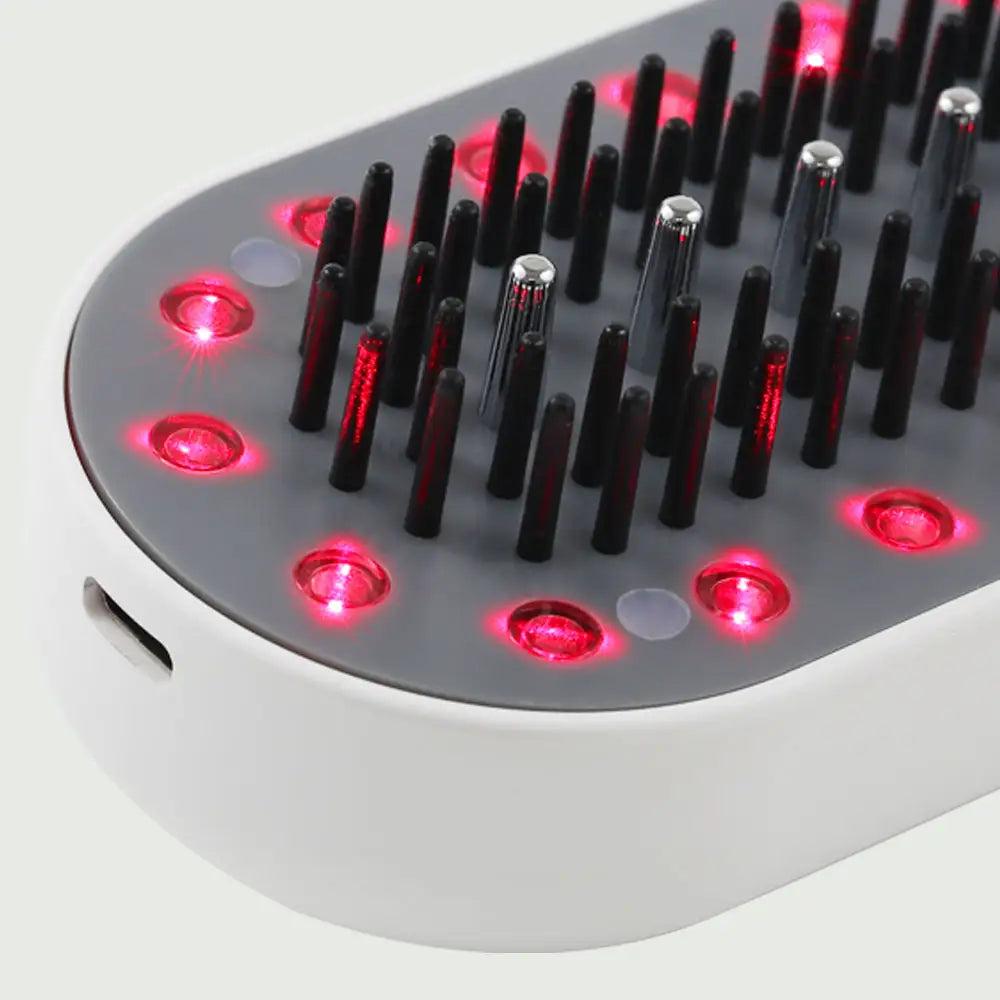 Closeup view of the Plasma Laser Therapy Hair Growth Comb by re-nū Smart Beauty, showing red laser diodes and microcurrent comb teeth