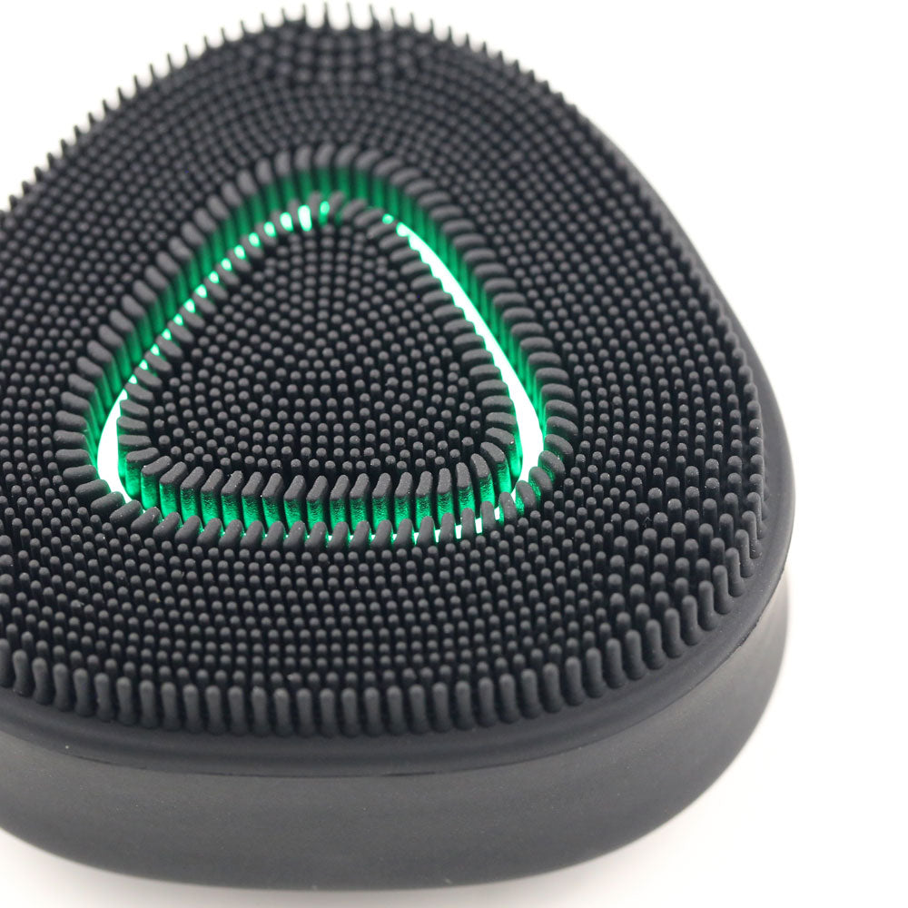 Close up view of Black PurePulse Pro Sonic Cleansing Brush featuring soft silicone bristles and an illuminated green LED light ring, designed for deep facial cleansing and rejuvenation