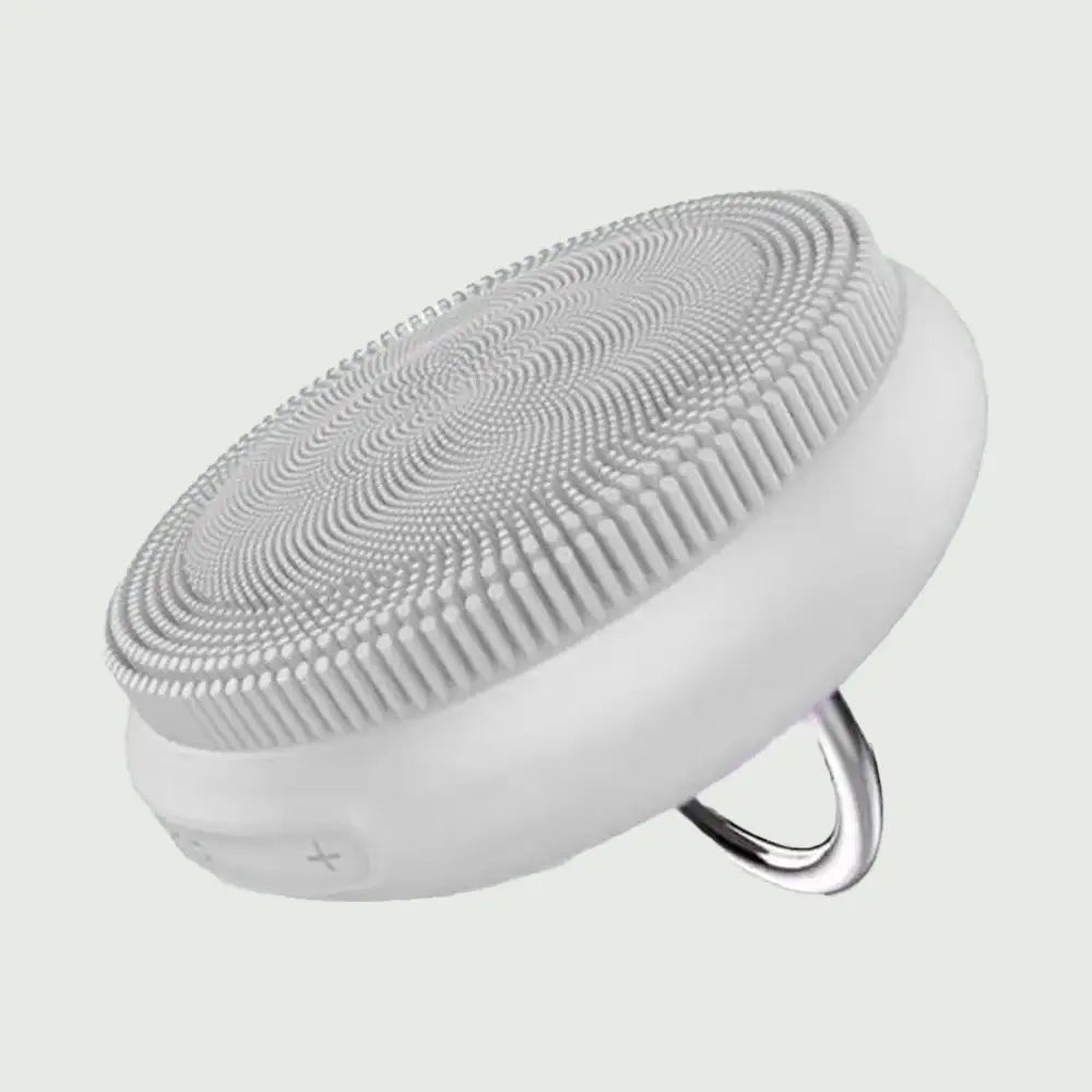 A side view of the PurePulse Sonic Cleansing Brush showing it's textured bristles and a silver ring handle, for deep pore cleansing and gentle exfoliation.