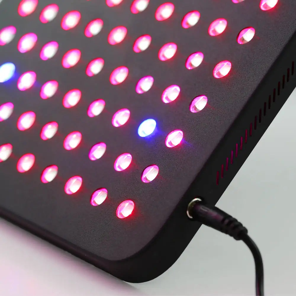 Closeup view of the LED Red Light Therapy Panel Elite – UltraThin, fully lit with red, near-infrared, and blue LEDs in all modes, showcasing its slim, modern design and easy-to-use power cord port.