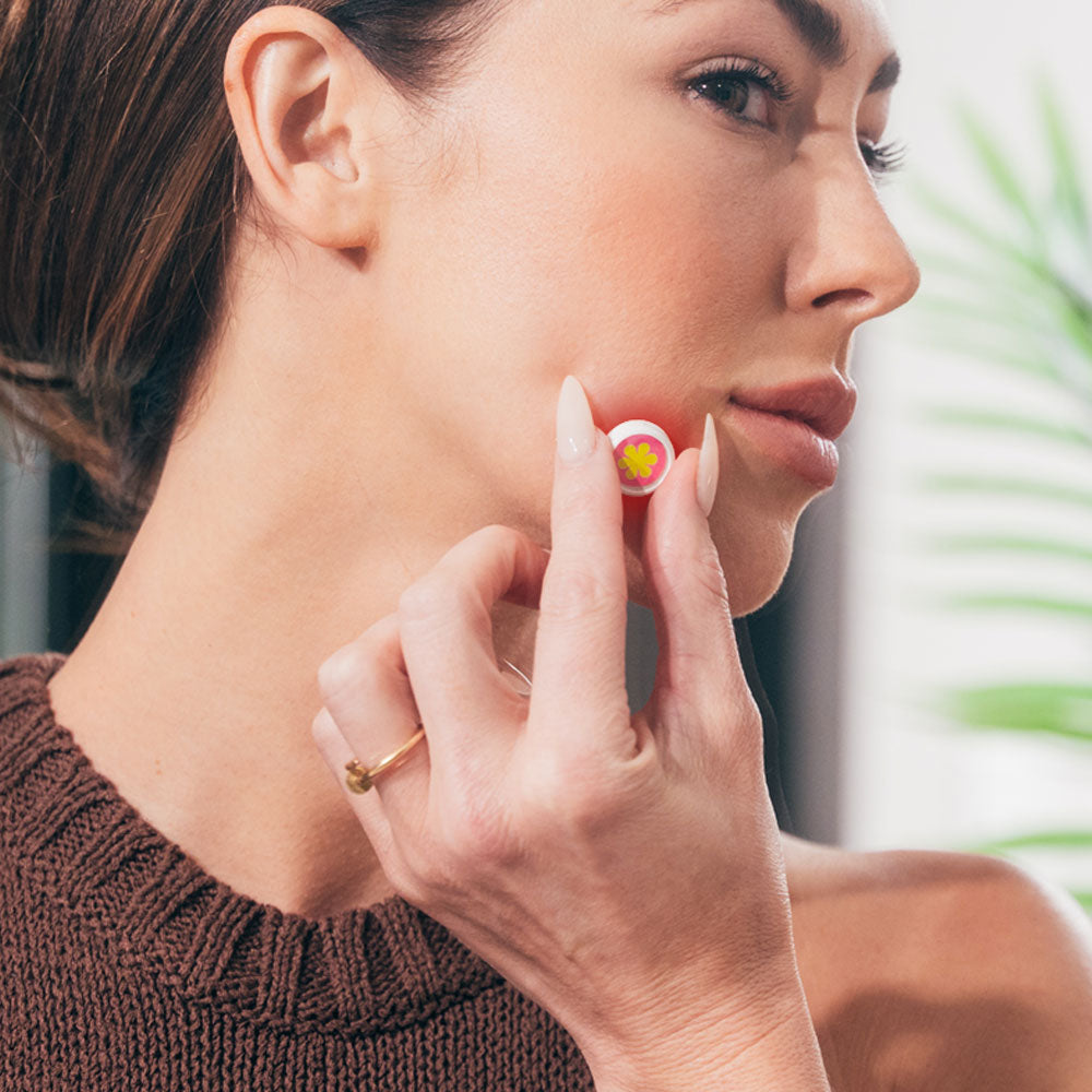 Woman applying GlowUp LED acne patch to cheek for targeted scar treatment