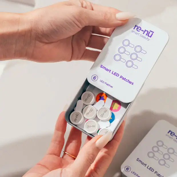 Close-up of a woman's hands opening the GlowUp acne LED patch packaging, revealing the patches, stickers and easy-to-use adhesive application tabs.