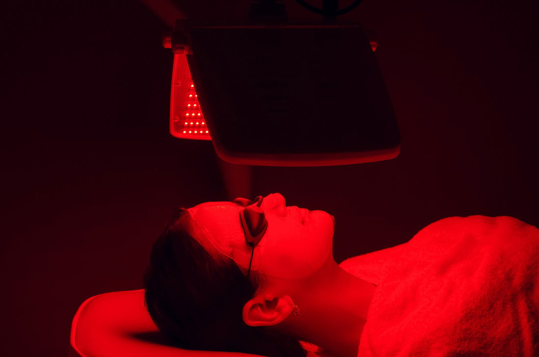 a woman under a red light therapy device