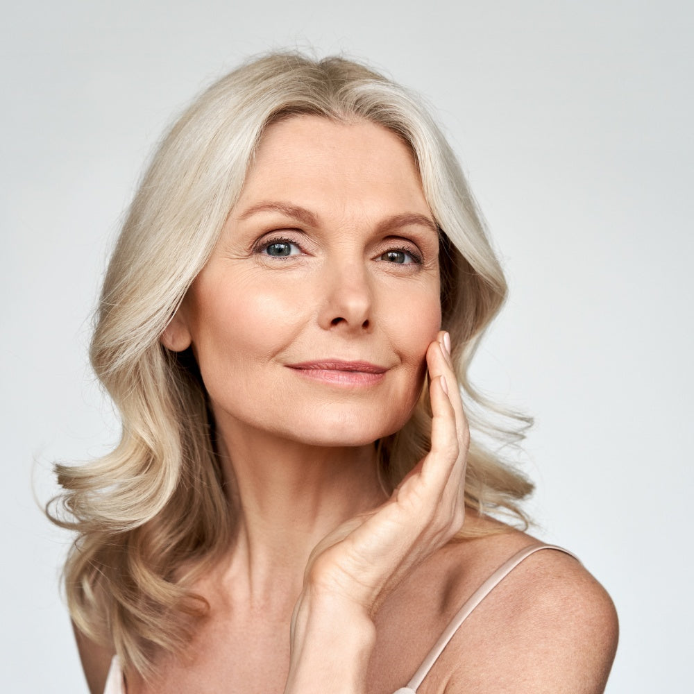 A woman with a radiant face wearing a white shirt, showcasing the benefits of Mask LED Light Therapy.