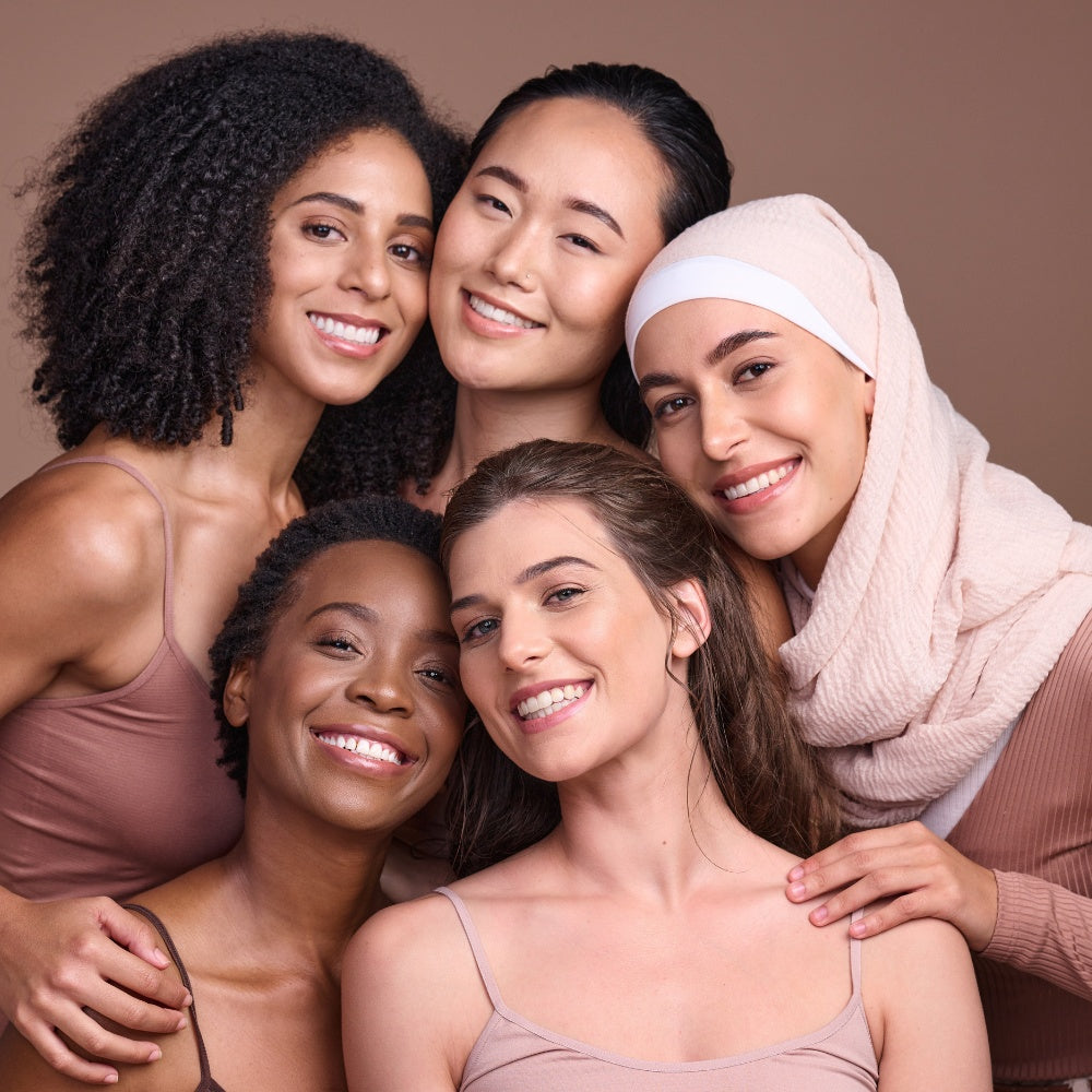 A diverse group of women smiling and posing together, showcasing friendship and unity in a vibrant setting.