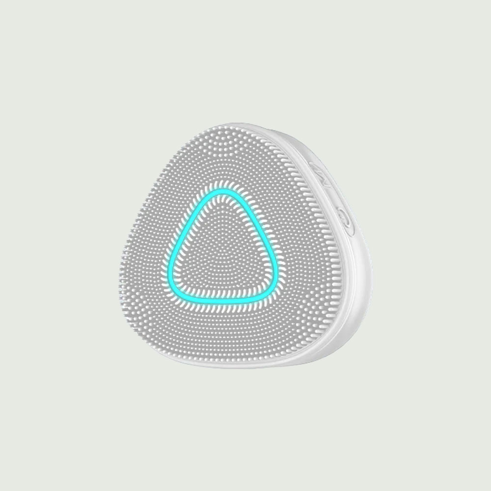 Close-up of a triangular Purepulse Pro sonic cleansing brush with soft silicone bristles and an illuminated blue LED ring, designed for deep facial cleansing and exfoliation