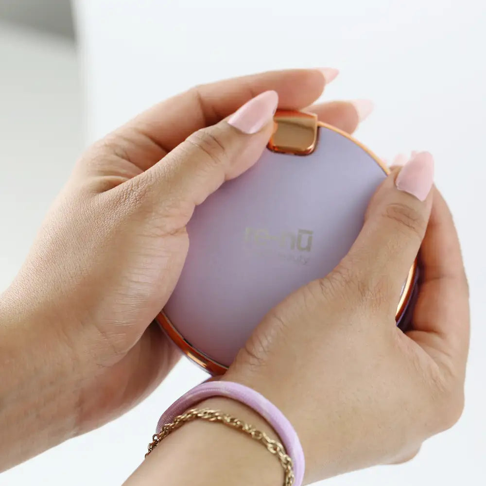 Closeup of a woman warming her hands with the 3-in-1 Hand Warmer, Compact Mirror & Power Bank.