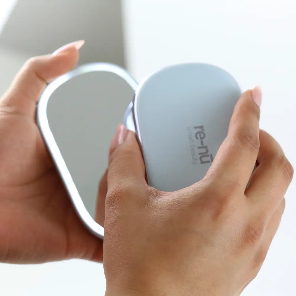 Closeup of a woman's hands holding he 4-in-1 Compact Mirror with Power Bank & Hand Warmer, highlighting the magnetic top and bright LED light.