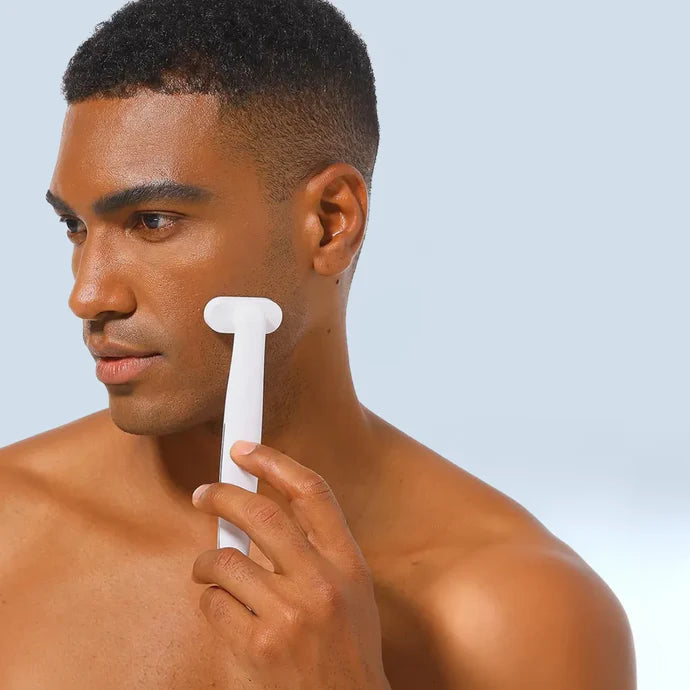 A man holds a white LED Light Therapy Wand with Microcurrent to his face, receiving LED Light Therapy