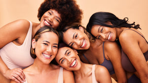 Five women in bras pose together, showcasing confidence and beauty, with a focus on skin care and self-expression.