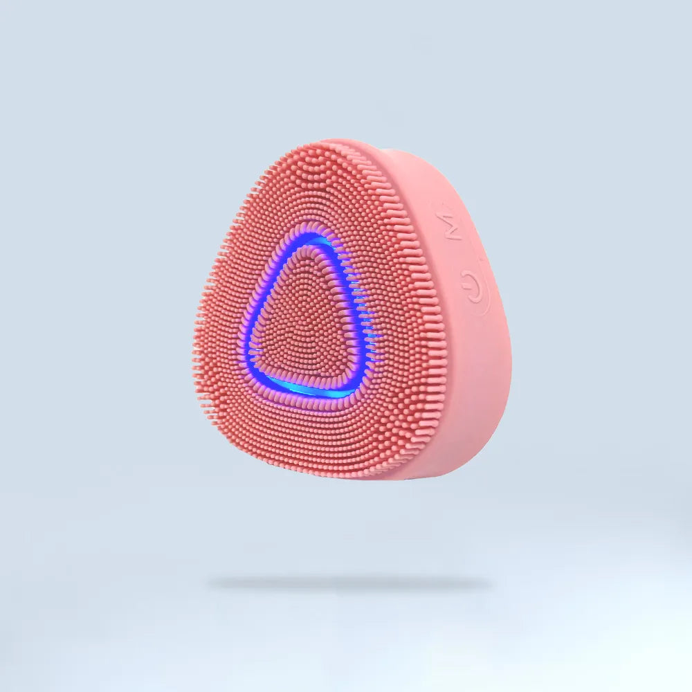 A pink silicone facial cleansing device featuring a blue LED light, designed for deep pore cleansing and LED light therapy skincare treatments.