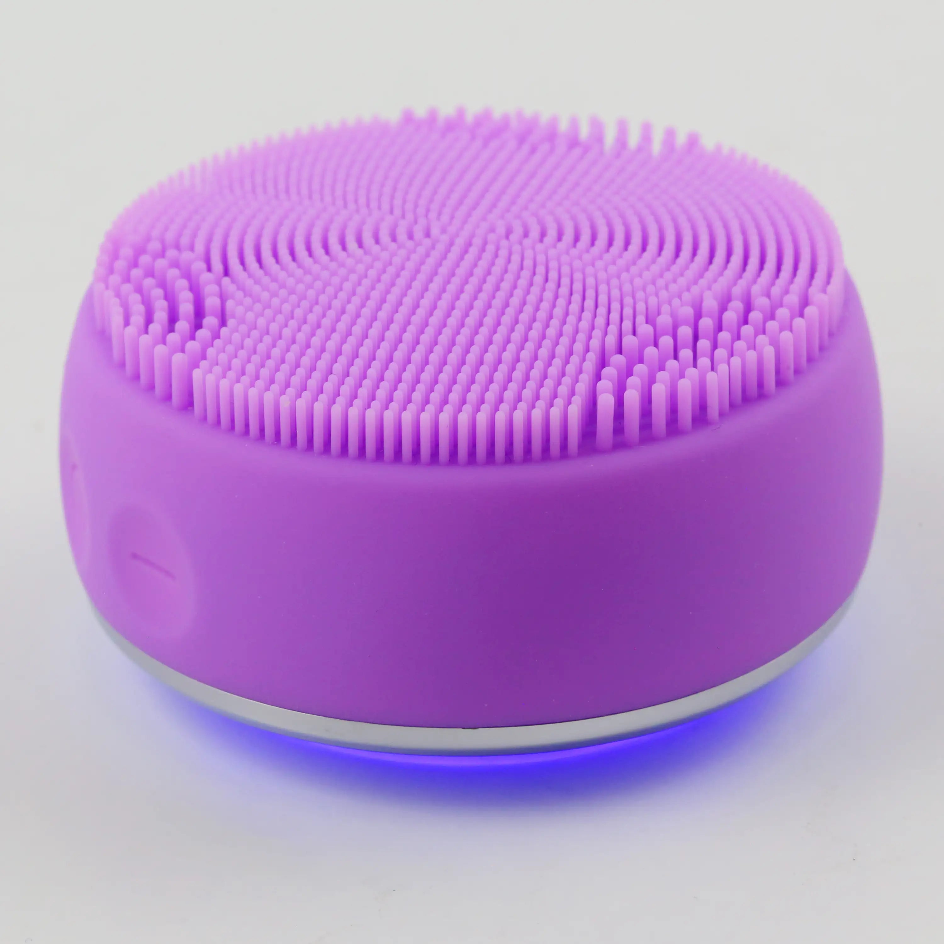 PurePulse Pro Plus Sonic Cleansing Brush resting face down with chrome EMS head exposed and blue LED glow reflecting across the surface below