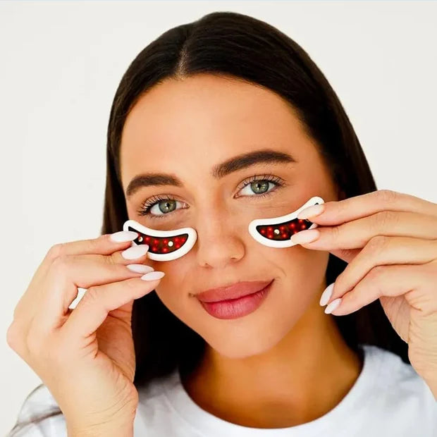 Woman wearing the GlowUp LED/EMS Under Eye Pads with visible red light glowing inside the pads, highlighting active treatment during use for under-eye rejuvenation.

