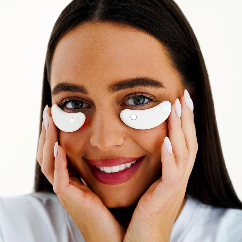 A woman with white eye makeup and eye patches, showcasing the benefits of LED light therapy for skin rejuvenation.