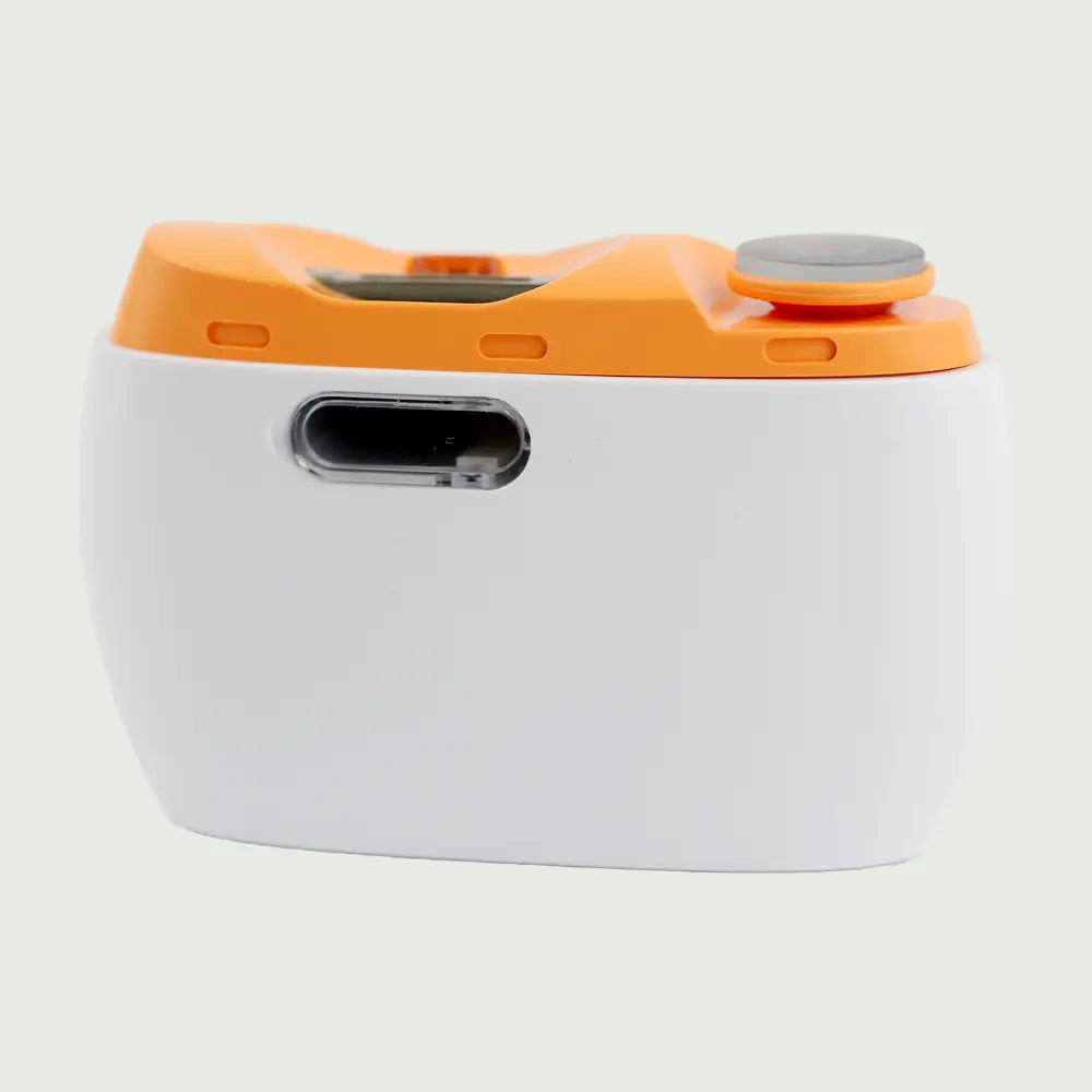 Electric nail trimmer with polisher on a surface, showing clean-out window and full device.