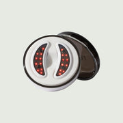 Front view of GlowUp LED/EMS Under Eye Anti-Aging Pads placed neatly in their sleek, round USB-C charging case.