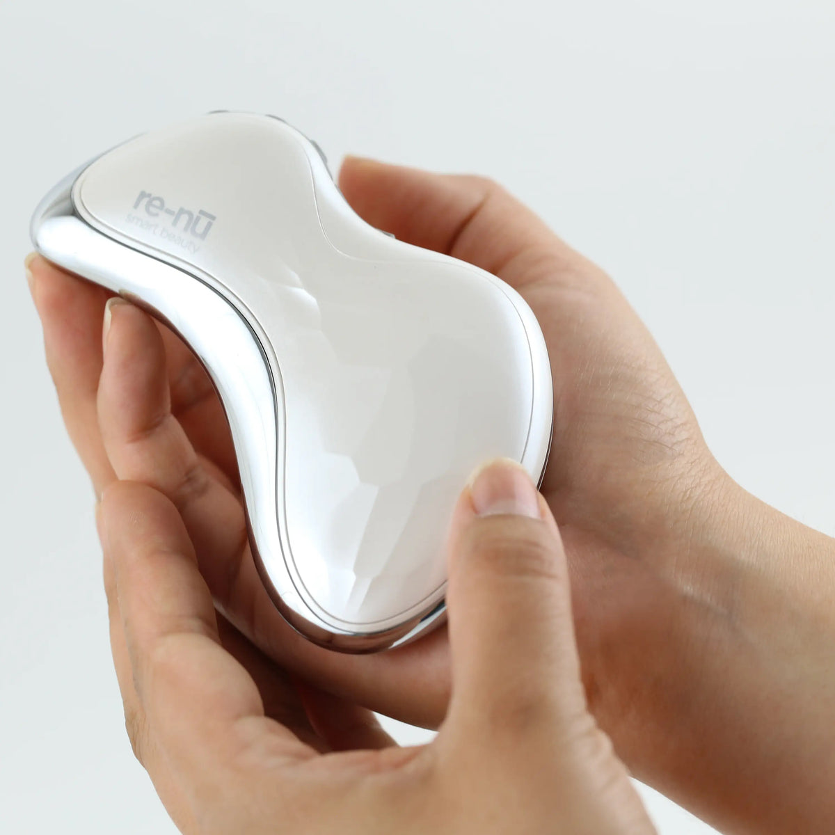 Heated Sonic Gua Sha Facial Massager resting in two cupped hands, highlighting its compact size, lightweight feel, and smooth, contoured shape.