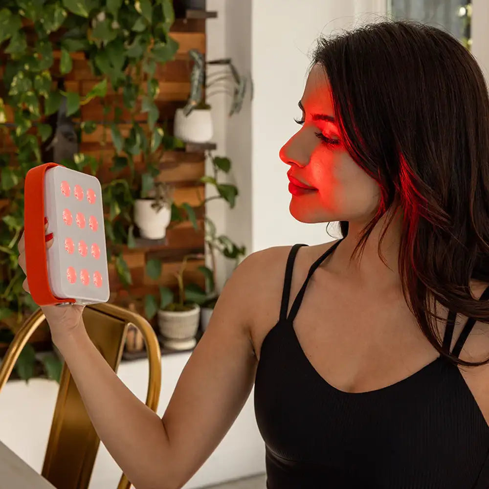 Woman using the Mini LED Red Light Panel on her face at home