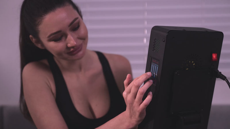 Red light therapy device in use at home, showing glowing LED panels delivering treatment to the face and body.