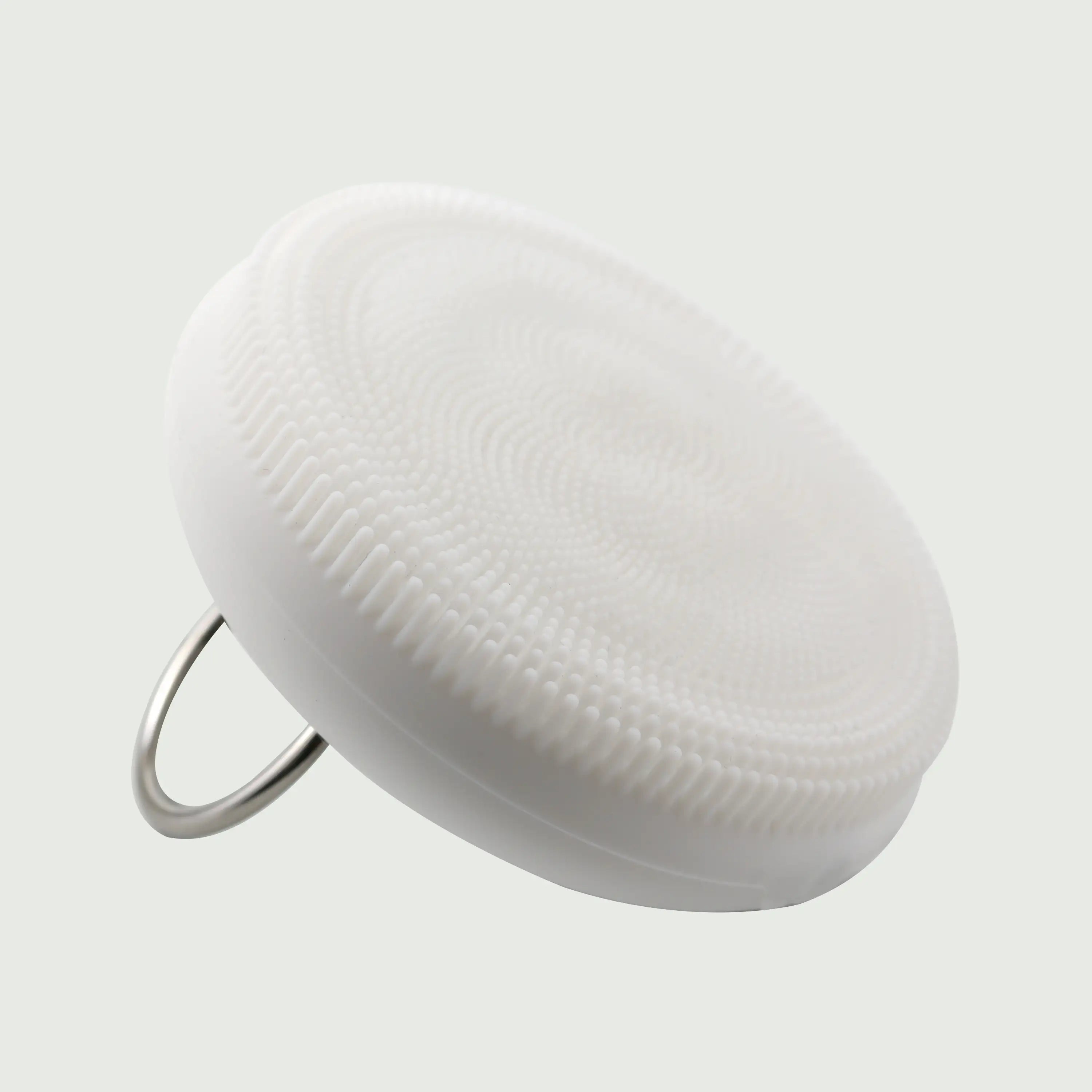 A side view of the PurePulse Sonic Cleansing Brush showing it's textured bristles and a silver ring handle, for deep pore cleansing and gentle exfoliation.