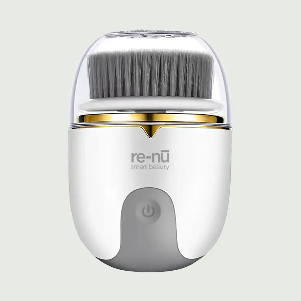 Front view of re-nū Smart Beauty PureSpin Rotating Facial Cleansing Brush with protective cap, soft gray bristles, and power button – waterproof, rechargeable skincare device.