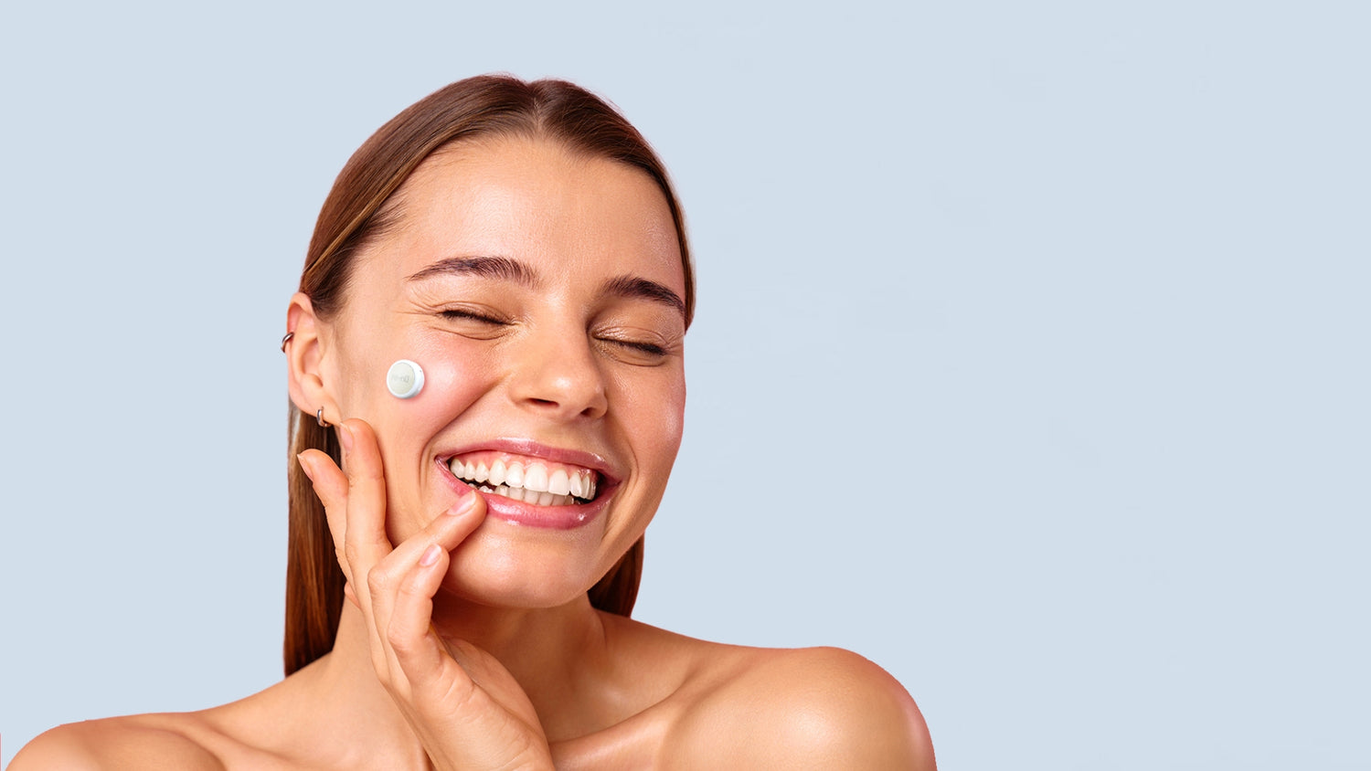 A cheerful woman holds GlowUp Post-Acne LED Patch to her face, radiating happiness and embracing a skincare routine.