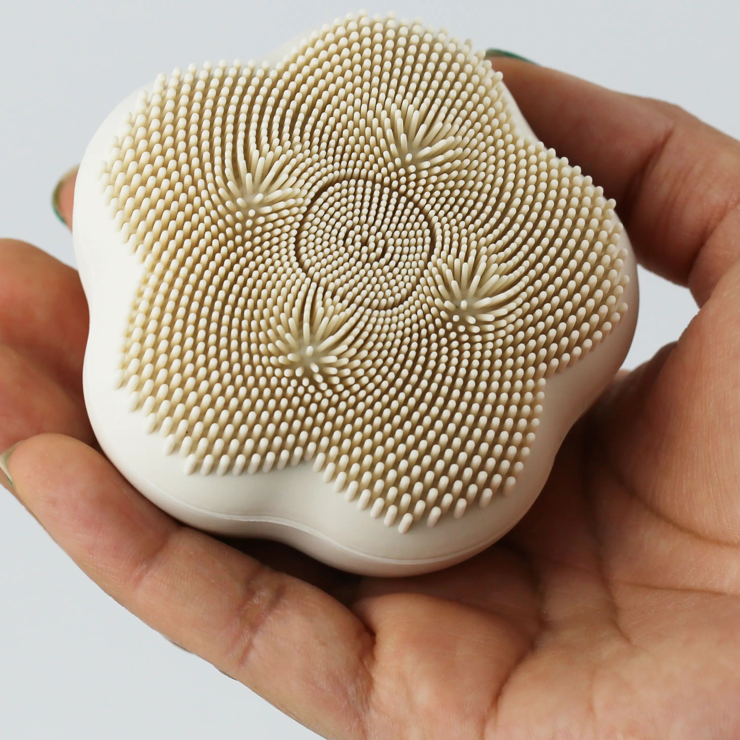 A woman’s hand cradling a compact sonic facial cleansing brush, emphasizing its ergonomic, handheld design.