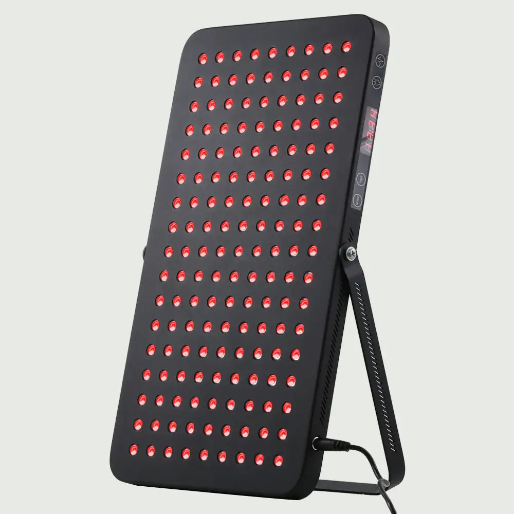Angled view of the LED Red Light Therapy Panel Elite – UltraThin, fully lit with red LEDs, supported by its stand and showcasing its slim, modern design.