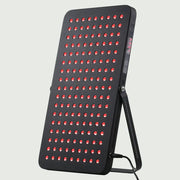 Angled view of the LED Red Light Therapy Panel Elite – UltraThin, fully lit with red LEDs, supported by its stand and showcasing its slim, modern design.